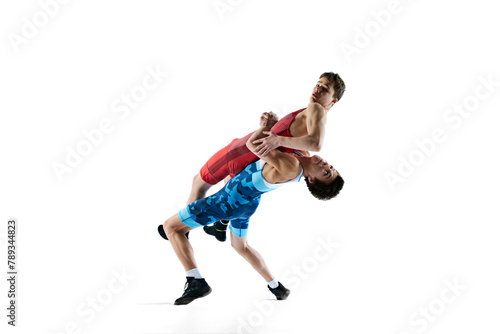 Male wrestlers, athletes wrestling in dynamic and intense match, showing athleticism and determination isolated on white background. Concept of combat sport, martial arts, competition, tournament