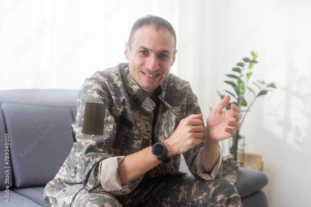 Naklejka premium excited army soldier sitting on couch at home