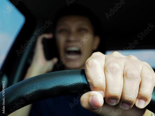 Asian man talking on the phone and getting angry and irritated while driving. Problems from traffic jams or car breakdowns