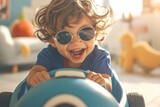 happy toddler boy wearing sunglasses and jeans riding toy car
