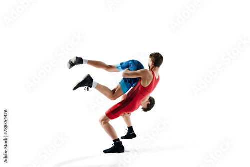 Young men  wrestlers showing athleticism and determination as they grapple isolated on white background. Concept of combat sport  martial arts  competition  tournament  dynamics