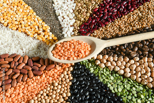 Wooden spoon with raw red lentils on various grain