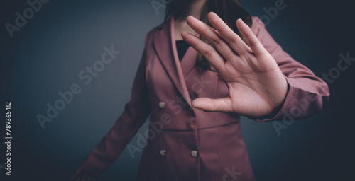 A businesswoman in a pink suit holds her hand out to stop something.