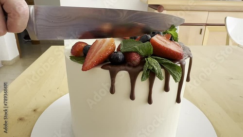 White cut cake with strawberry filling and decorate by strawberry and blueberry close up. Big beautiful cake for  birthday. Care cut and it is seen all teasty layers of cream, biscuit and jem photo