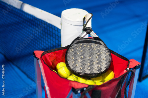 Black professional paddle tennis racket and ball with natural lighting on blue background. Horizontal sport theme poster, greeting cards, headers, website and app photo