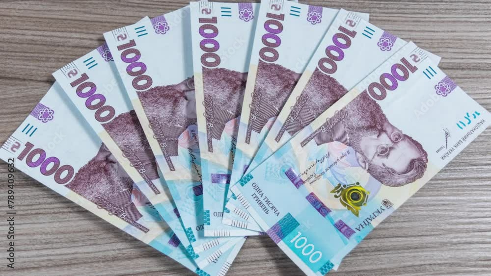 Ukrainian thousand-hryvnia banknotes laid out on the table are collected in a pile and then laid out again. The concept of income, business and earnings. Stop motion animation. Ukrainian thousand-hryvnia banknotes laid out on the table are collected in a pile and then laid out again. The concept of income, business and earnings. Stop motion animation.