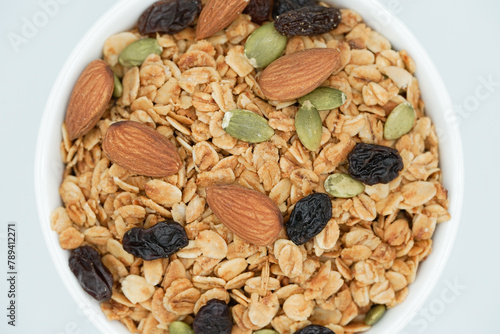 Top view of Homemade granola with mix nuts in a white bowl. Healthy snack and breakfast.