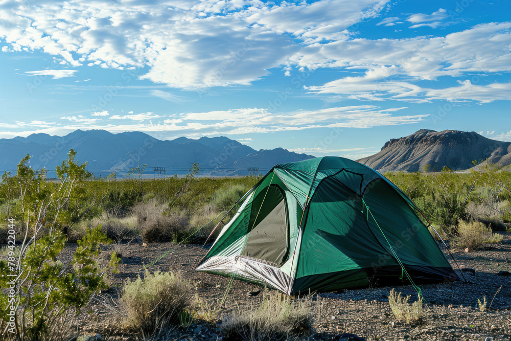 green camping tent set up in the wilderness high desert with mountains and blue sky. perfect for outdoor activities or camping adventures
