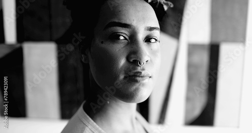 African American young woman dramatic black and white portrait looking at camera with empowered serious expression. 20s adult girl feeling confident and strong in monochrome