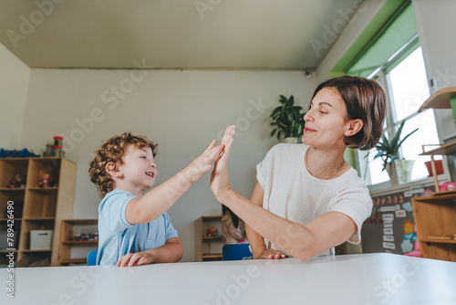 Teacher giving high five to a little boy in kindergarten