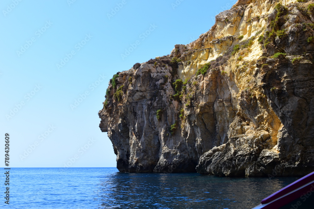 ZURRIEQ, MALTA - Augusts 06, 2021: The Blue Grotto - A famous sea cave surrounded by the deep blue sea at southern Malta. On a traditional boat surrounded by more brightly coloured boats. 
