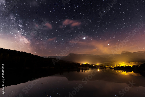 Night view of the Maroño reservoir, Alava, with the starry sky, the Milky Way and Sierra Salvada reflected in the water of the reservoir photo