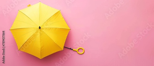 An umbrella in yellow on a pastel pink background.