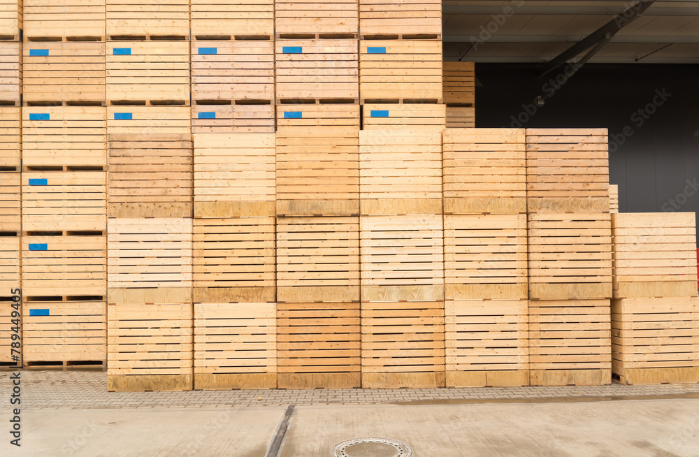 Many large wooden boxes for transporting potatoes or apples are stacked one on top of the other in front of the warehouse. Many large wooden boxes for transporting potatoes or apples are stacked one on top of the other in front of the warehouse.