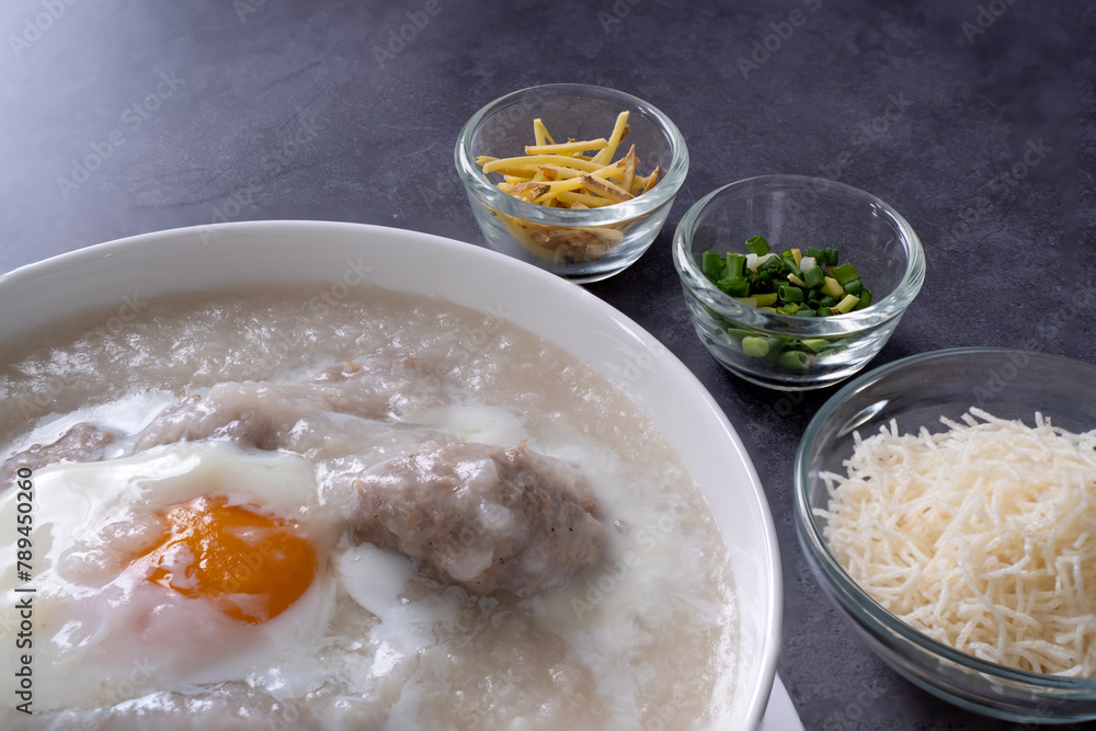 Hot Thai congee (rice porridge) with minced pork ball and boiled egg as breakfast. Hot Thai congee (rice porridge) with minced pork ball and boiled egg as breakfast.