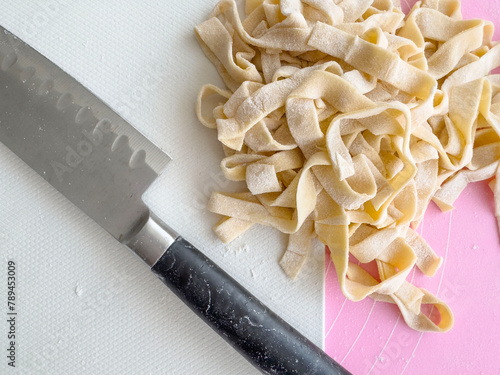 hand cut raw pasta and knife on cutting board