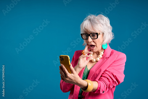 Surprised Senior Woman Using Smartphone in Pink Blazer