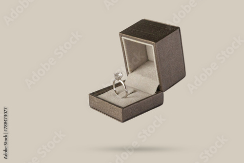 Diamond ring in jewelry gift box floated on brown background