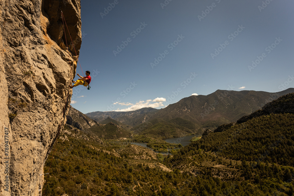 A man is climbing a rock face with a view of mountains in the background. The scene is adventurous and exciting, with the man's focus on reaching the top of the rock