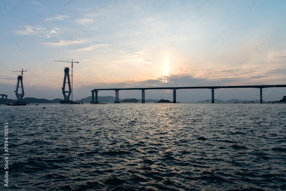 constructing the bridge on the sea during sunset constructing the bridge on the sea during sunset