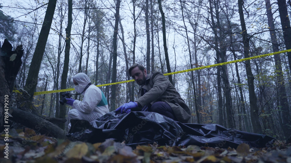 Police officer arrives at the crime scene to inspect the victim's body for evidence Police officer arrives at the crime scene to inspect the victim's body for evidence