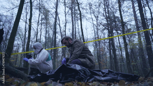 Detective examines the body of a victim of a maniac, with forensic experts analyzing the crime scene 