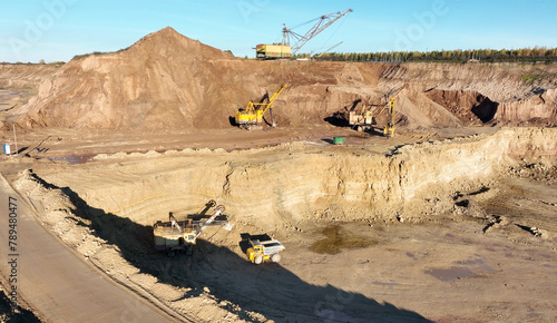 Excavator on earthmoving, aerial view. Open pit mining. Backhoe dig ground in quarry. Excavator load dolomite in haul truck, mining ore, drone view. Heavy machinery  on extracts rock or mineral.