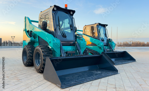 Skid steer loader for construction works. Сompact construction equipment for work in limited conditions. Road repair at construction site, city streets. Bobcat skid-steer loader for roadworks. photo