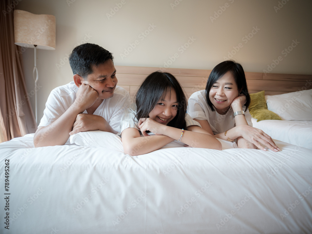 Parents and daughter reclined comfortably on a soft bed. in the hotel. Family vacation on vacation - obrazy, fototapety, plakaty 