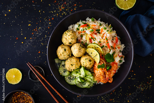 Meatballs served with white rice and marinated sliced cucumber on wooden background 