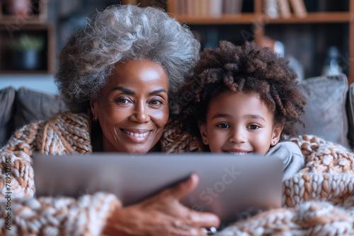 Grandmother and her afro granddaughter looking at a computer smiling