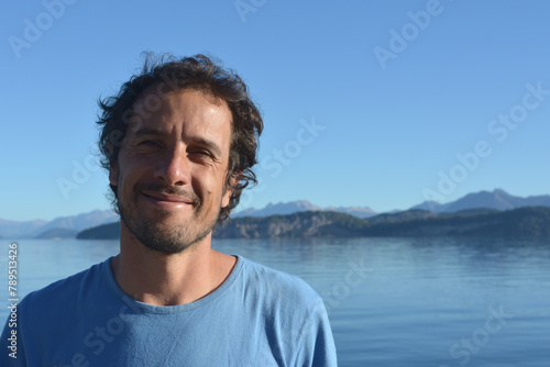 smiling latin american brown haired man on vacation outdoors with lake and mountains