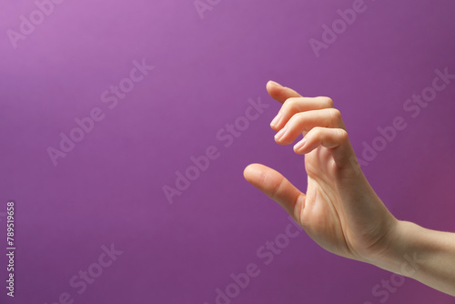 Woman holding something in hand on purple background, closeup. Space for text