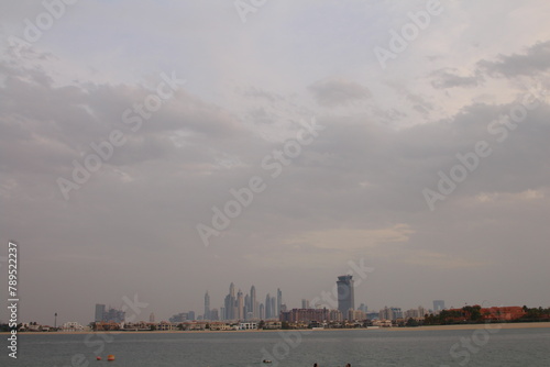 A city skyline with a body of water and a few clouds
