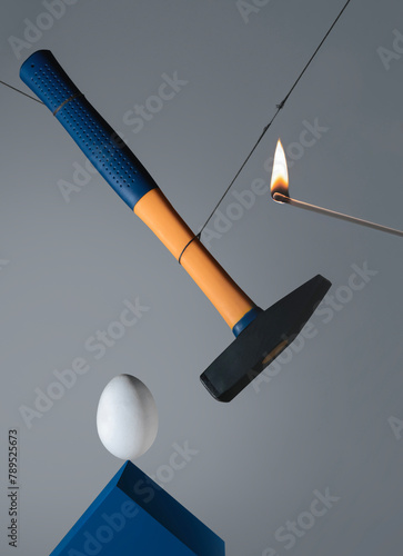 Abstract composition with egg, hammer, burning match. A second before. photo