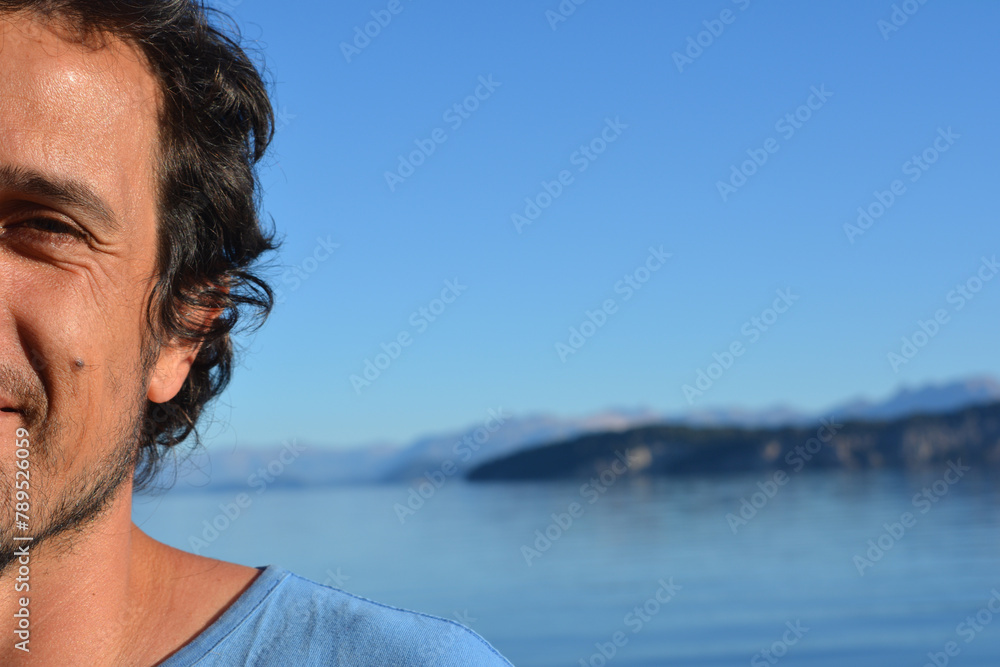 half portrait of brown haired man on vacation outdoors with lake and mountains