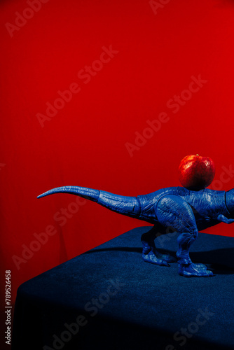 Blue Toy Dinosaur Positioned Next to a Red Apple  photo