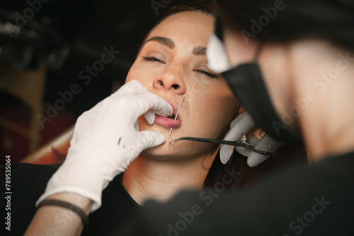 Woman giving a piercing to woman photo