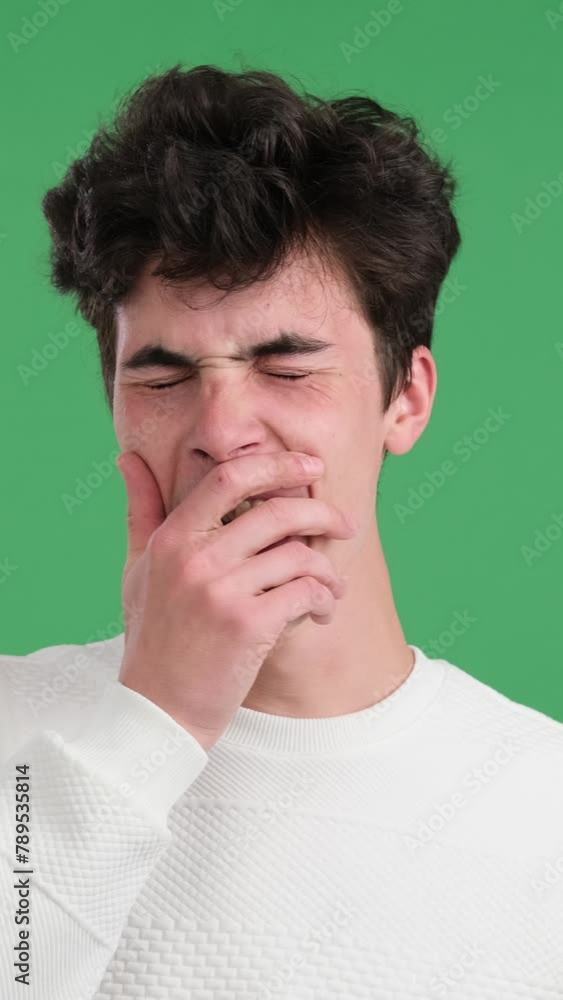 Portrait of a weary and sleepy Caucasian young man yawning over green background. Concept of a sleepless and tiredness. Vertical video. Portrait of a weary and sleepy Caucasian young man yawning over green background. Concept of a sleepless and tiredness. Vertical video.