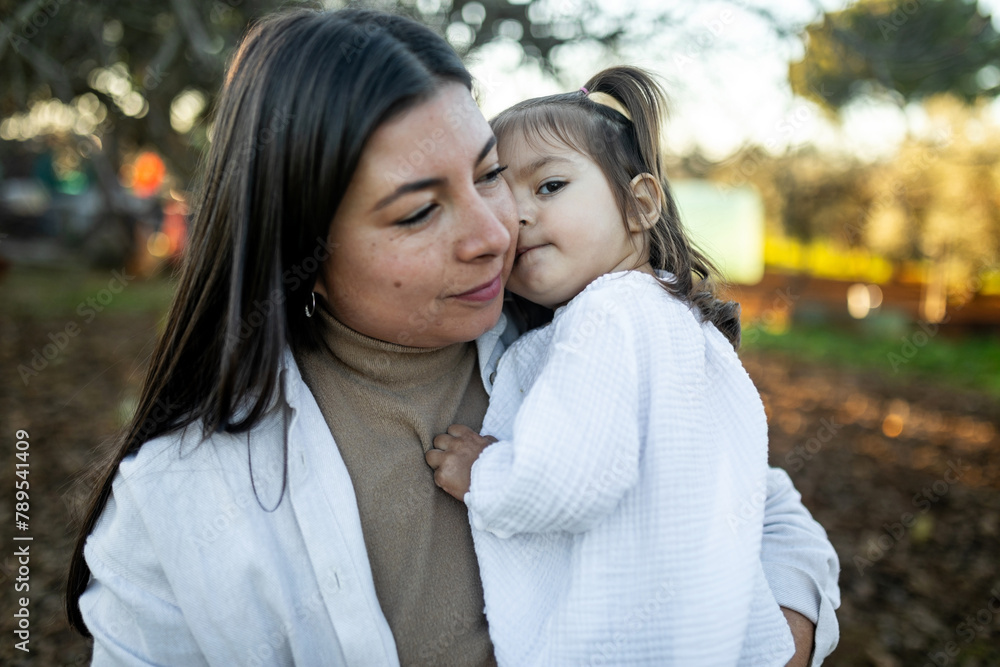 young mother tenderly hugging her daughter in nature young mother tenderly hugging her daughter in nature