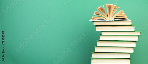 Open book, hardback books on wooden table, on a green background. Back to school. Copy space for text. Education background. panorama, banner.