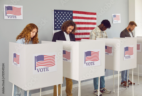 Foto Portrait of a group of young happy diverse American citizens people men and women standing at vote center with USA flags in voting booth putting their ballots in bin on election day