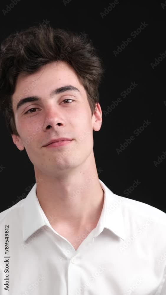 Portrait of a positive and successful Caucasian young man, looking at camera, on black background. Smiling businessperson concept. Vertical video. Portrait of a positive and successful Caucasian young man, looking at camera, on black background. Smiling businessperson concept. Vertical video.