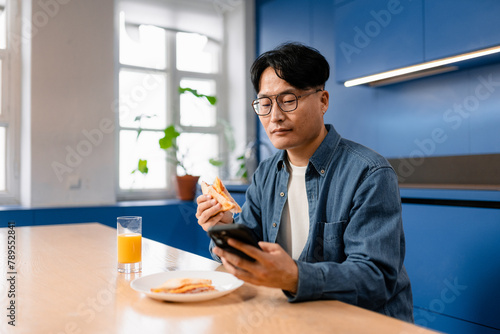 A man eats sitting in the kitchen photo