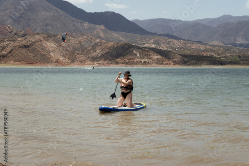 Woman in life jacket at sub board at river at evening photo