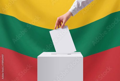Elections, Lithuania. A hand throws a ballot into the ballot box. The flag of Lithuania on the background. Voting concept.