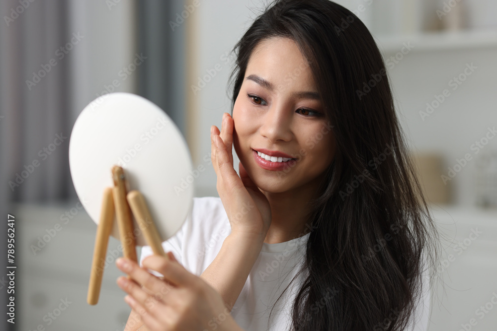 Woman with perfect skin looking at mirror indoors Woman with perfect skin looking at mirror indoors