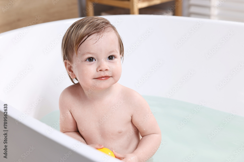 Cute little child bathing in tub at home