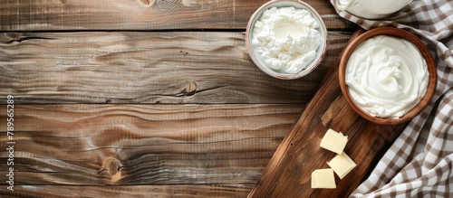 Wooden table with dairy products. Sour cream, milk, cheese, yogurt, and butter displayed from a top view with space for text.