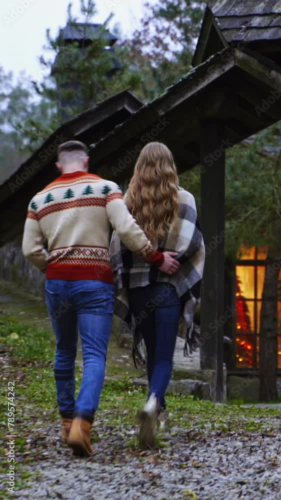 Backside view of a young couple. Lovely people returning from the date outdoors in warm autumn day. Back view of a pretty couple coming into the yard of the cottage. Vertical video